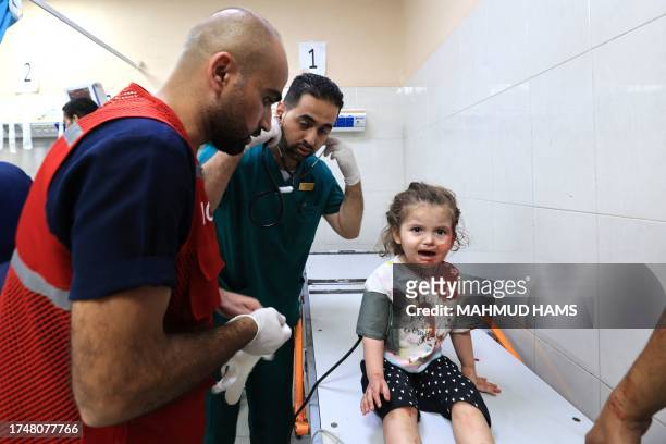 Palestinian nurse Mahmud al-Astal arrives to attend to a little girl with a head wound as she sits on an examining table at the Nasser hospital...