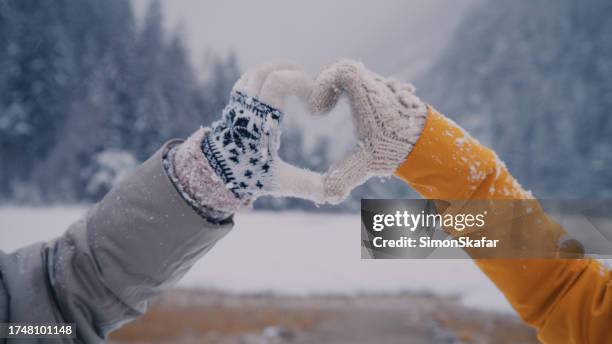 two women making heart sign gesture in knitted woolen winter gloves on cold winter day - mitten glove stock pictures, royalty-free photos & images
