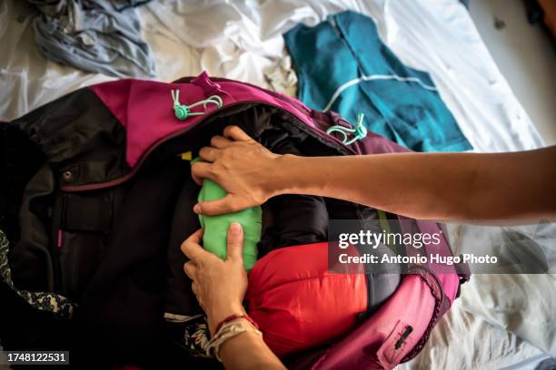 hands of a woman packing clothes into an adventure backpack for travel. - mochila-bolsa fotografías e imágenes de stock