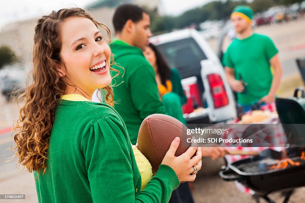 Cute college girl tailgating at stadium with football fans