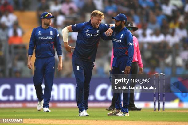 David Willey of England is helped by teammate Adil Rashid as he appears to pick up an injury during the ICC Men's Cricket World Cup India 2023 match...