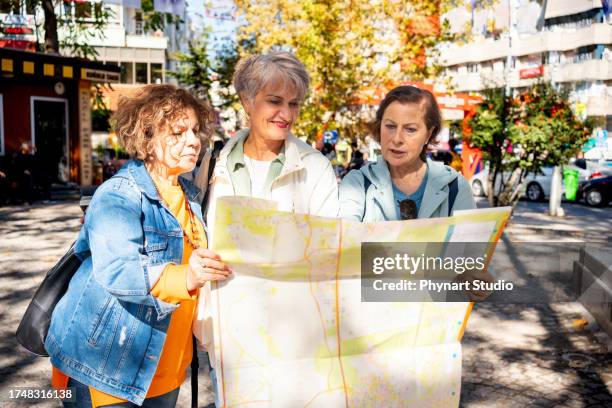 reife frauen reisende besichtigen die stadt während eines urlaubs mit einem stadtplan - reiseführer stock-fotos und bilder