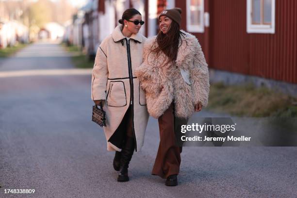 Benthe Liem seen wearing a black sunglasses, silver pearl earrings, white cream fluffy long coat with black contrast seams, beige / black logo...