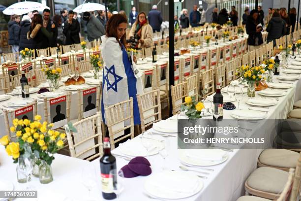 People come to view the empty places laid out for the 220 hostages at a 'Shabbat' table in the JW3 Piazza in north London on October 27 as people are...