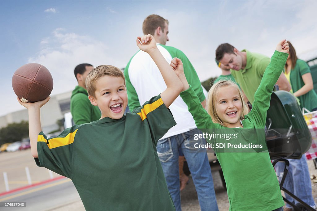 Excited children cheering at tailgate party during college football game
