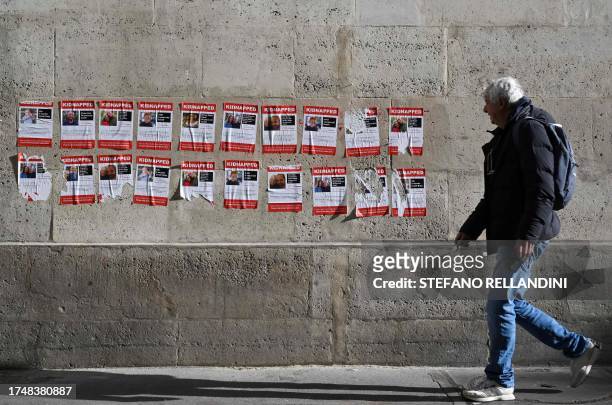 Man walks past placards, showing recently abducted or missing Israelis, to symbolise young hostages taken by Hamas militant, in central Paris on...