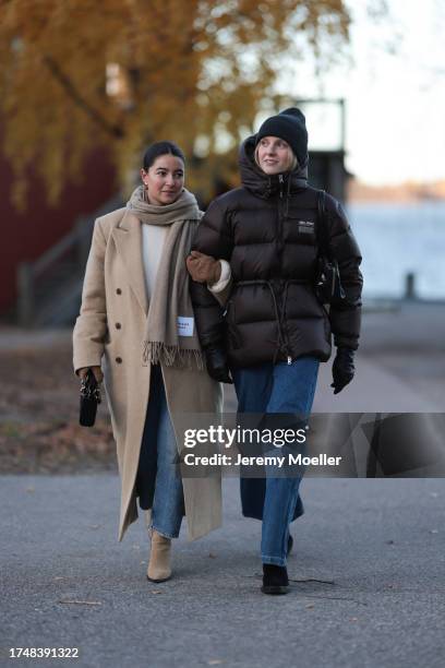 Benthe Liem seen wearing gold earrings, beige wool knit scarf, white cream wool knit pullover, beige long coat, brown suede leather gloves, light...