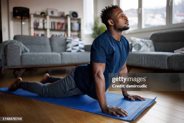 man practicing yoga, stretching muscles, lying in cobra pose - cobra stock pictures, royalty-free photos & images