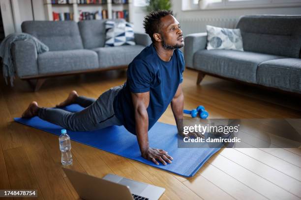 man practicing yoga, stretching muscles, lying in cobra pose - cobra stretch stock pictures, royalty-free photos & images
