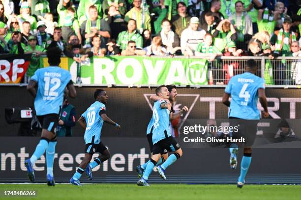 Alex Grimaldo of Bayer Leverkusen celebrates with teammates after scoring the team's second goal during the Bundesliga match between VfL Wolfsburg...