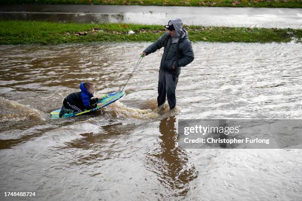 Man pulls a boy on a body board through flood water in the Pentagon area of Derby after the River Derwent burst its banks during storm Babet on...
