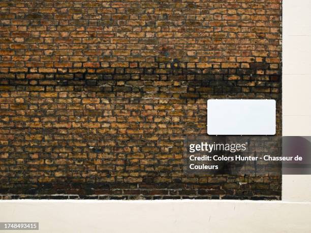 weathered brown brick and beige painted concrete wall with empty and white street sign in london, england united kingdom - commercial sign stock illustrations stock pictures, royalty-free photos & images