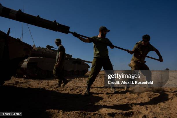 Soldiers clean the barrel of a tank on October 21, 2023 in Southern Israel. Today marks two weeks since the kibbutzim and communities around the Gaza...