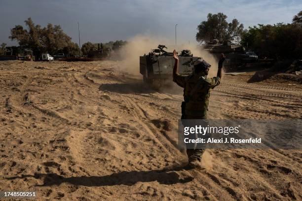 An IDF soldier guides an armored personnel carrier on October 21, 2023 in Southern Israel. Today marks two weeks since the kibbutzim and communities...