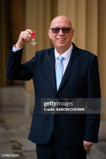 Broadcaster Ken Bruce poses with their medal after being appointed a Member of the Order of the British Empire following an investiture ceremony at...