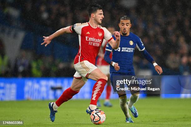 Declan Rice of Arsenal runs with the ball whilst under pressure from Malo Gusto of Chelsea during the Premier League match between Chelsea FC and...