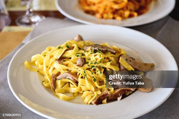 close up of tasty tagliatelle with porcini mushrooms on a plate in a restaurant. - eekhoorntjesbrood stockfoto's en -beelden
