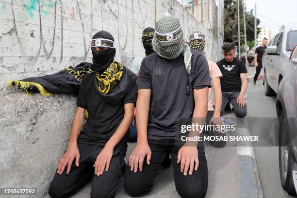 Palestinians wearing the emblem of the Islamic Jihad group kneel to pay along a pavement during a demonstration in the occupied West Bank city of...