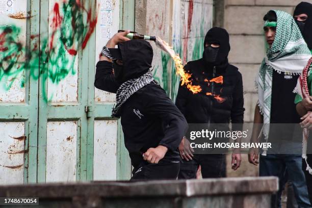 Palestinian youth hurls a Molotov cocktail against Israeli troops during confrontations with them following a demonstration in the occupied West Bank...