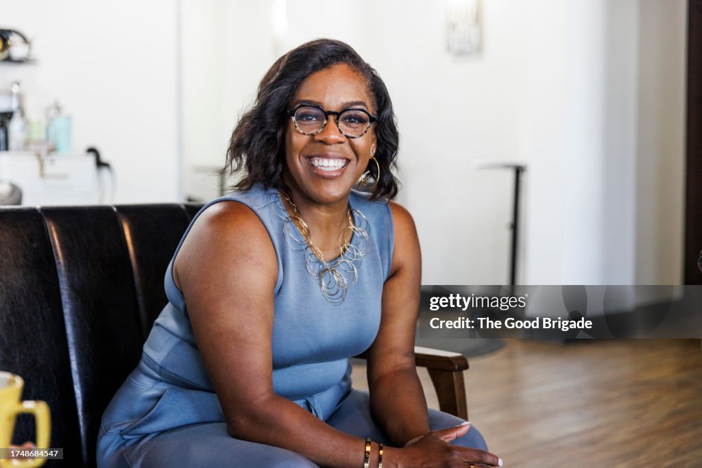 Portrait of smiling mature female hairdresser sitting at hair salon