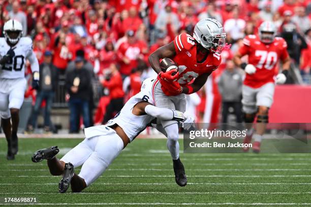 Marvin Harrison Jr. #18 of the Ohio State Buckeyes is tackled by Zakee Wheatley of the Penn State Nittany Lions during the second quarter of a game...