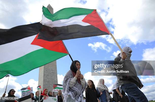 Pro-Palestinian protesters carry Palestinian flags as they march by the Washington Monument during a demonstration calling for a ceasefire in Gaza on...