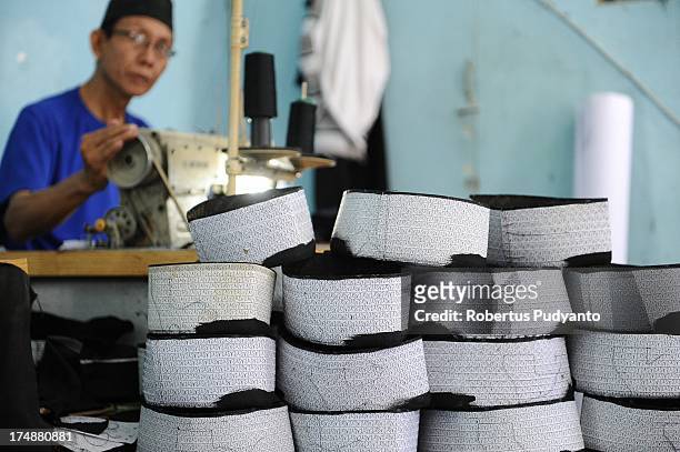 Workers finish sewing the body of skull caps at Awing traditional Muslim skull cap manufacturers on July 29, 2013 in Gresik, Java, Indonesia. Awing...