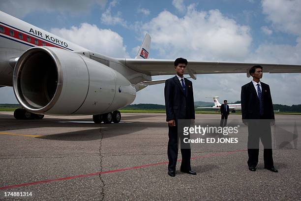Government minders stand before an Air Koryo aircraft on the tarmac at Pyongyang airport on July 29, 2013. North Korea marked the 60th anniversary of...