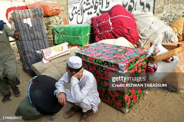 An Afghan refugee sits beside his belongings before loading them onto a bus at the Karachi bus terminal in Sindh province for his departure to...