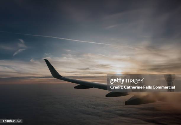 wing of an airplane mid air, flying through the clouds at sunset - windows stock pictures, royalty-free photos & images