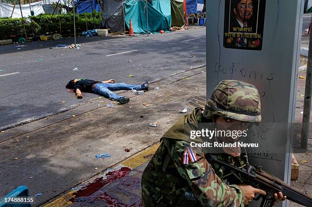 During the Thai military crackdown on the Red Shirt protest and occupation of central Bangkok. A soldier taking cover while a dead militant lay in...