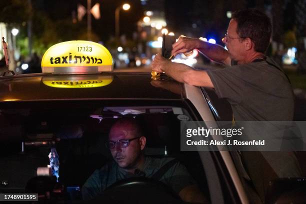 Demonstrator ties a yellow ribbon, which is being used to support the releasing of hostages captured by Hamas, onto a taxi in rally calling for the...