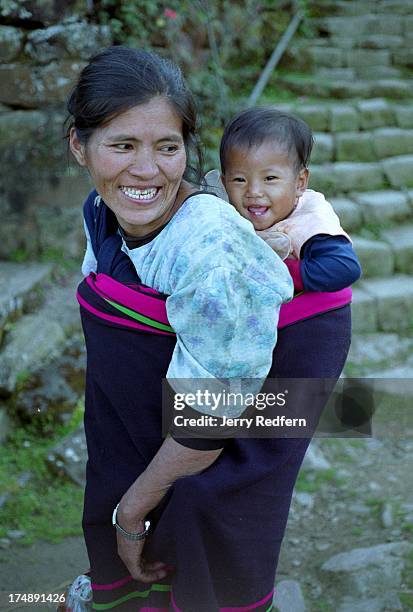 Naga woman carries her son home, wrapped in a thick, traditional Naga wool blanket. .