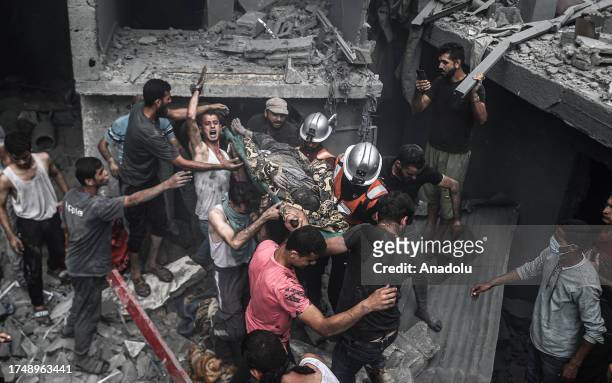 People carry injured and dead Palestinians from the rubbles of buildings as civil defense teams and civilians conduct search and rescue operations...