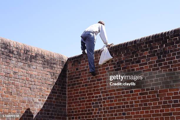 close-up of a thief climbing over a brick wall - prison escape 個照片及圖片檔