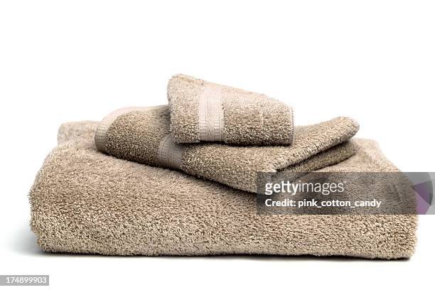 a pile of brown bath towels on a white background - towel stock pictures, royalty-free photos & images