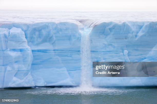 Waterfall at edge of the Brasvellbreen glacier from the ice cap Austfonna debouching into the Barents Sea, Nordaustlandet, Svalbard / Spitsbergen.