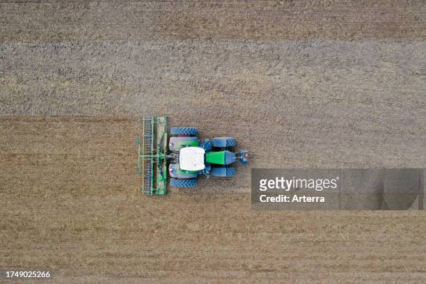 Tractor with rotary harrow, agricultural machine for seedbed cultivation after tillage, crumbling and aerating soil before planting a field in spring.