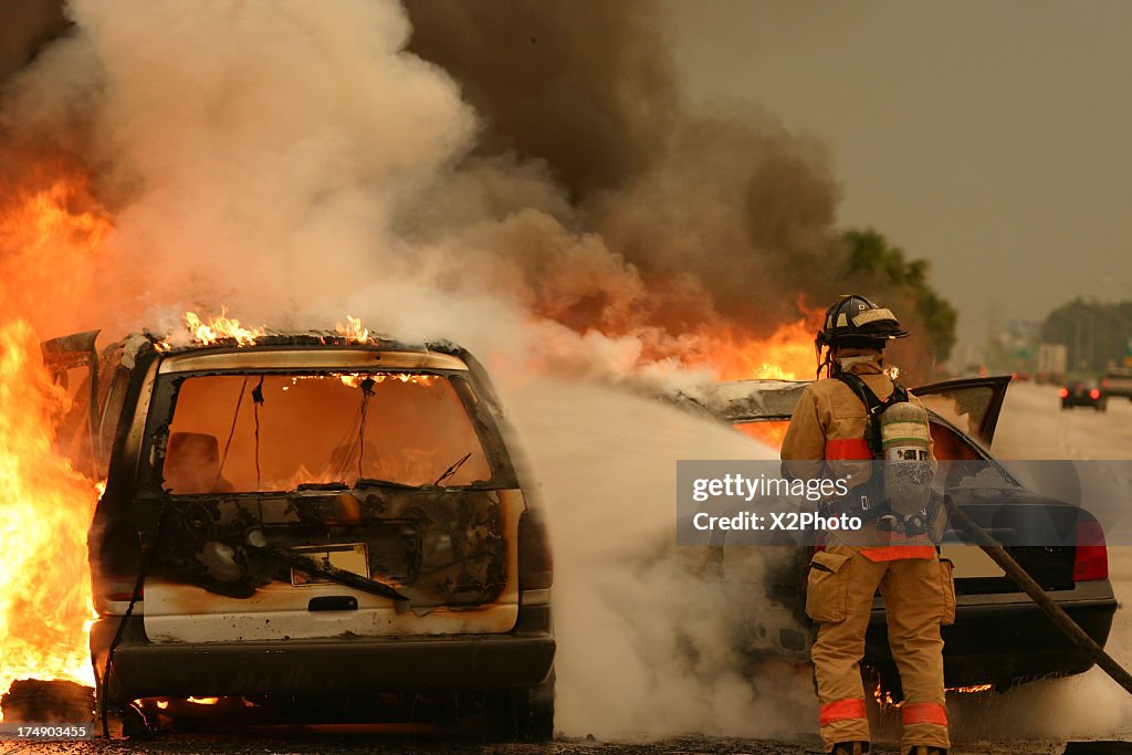 Firefighter extinguishing burning vehicle