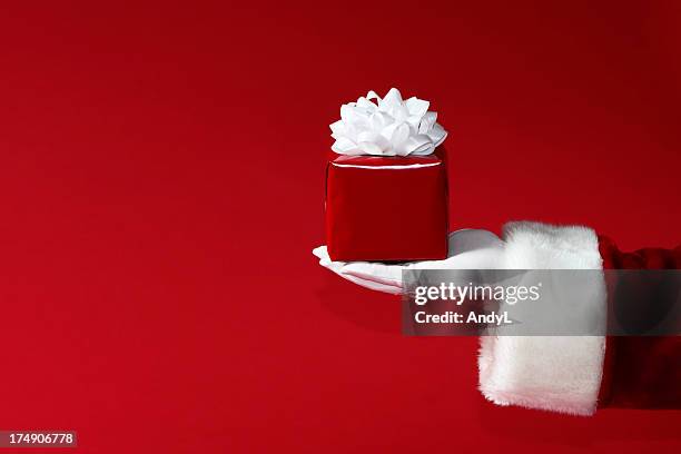 santa holding christmas gift on red - kerstman stockfoto's en -beelden