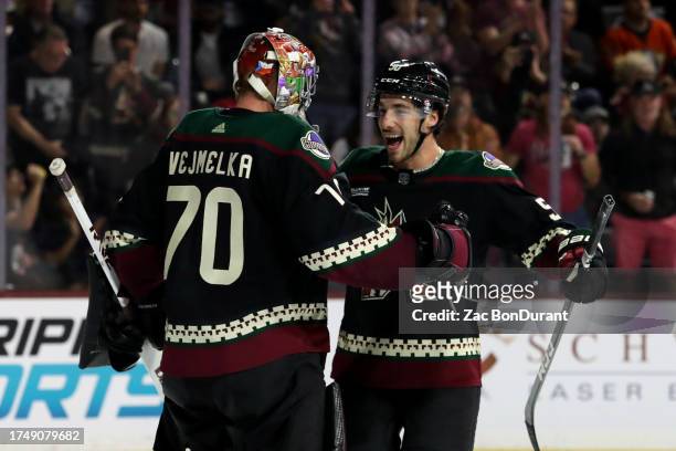 Sean Durzi of the Arizona Coyotes celebrates with Karel Vejmelka a 2-1 victory over the Anaheim Ducks at Mullett Arena on October 21, 2023 in Tempe,...