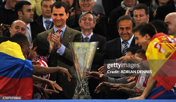 Spain's Prince Felipe and UEFA President Michel Platini applaud while Aletico Madrid's players celebrate with the trophy after winning the final...