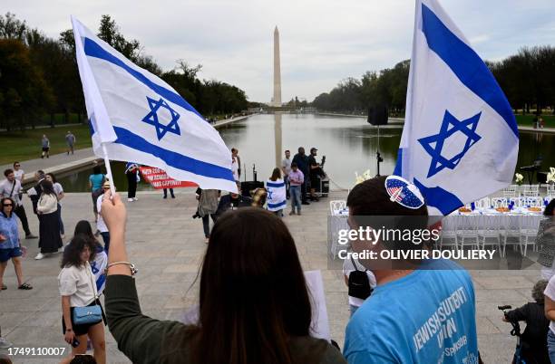 People wave Flags of Israel as a "Shabbat Dinner" table is prepared with 200 empty seats representing the Israeli hostages and missing people, at the...