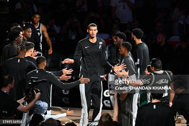 San Antonio Spurs' French forward-center Victor Wembanyama greets teammates as he walks into the court ahead of the NBA basketball game between the...
