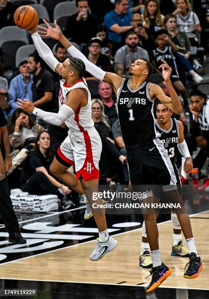 San Antonio Spurs' French forward-center Victor Wembanyama fights for the ball with Houston Rockets' Canadian guard-forward Dillon Brooks during the...