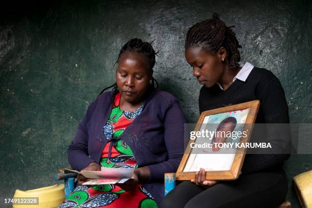 Rose Wanjiku reacts as she sits outside her residence with a relative looking at photos of her belated sister, Agnes, in Nanyuki town, Laikipia...