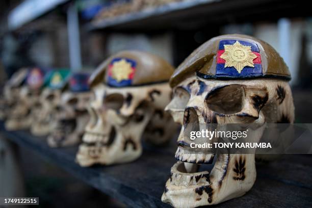 Display of carvings that depict human skulls in beret's bearing military insignia of various British Army companies that are a popular souvenir with...