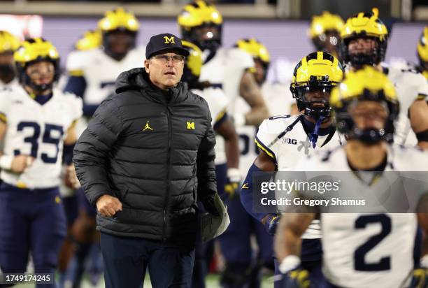 Head coach Jim Harbaugh of the Michigan Wolverines takes the field with his team to play the Michigan State Spartans at Spartan Stadium on October...