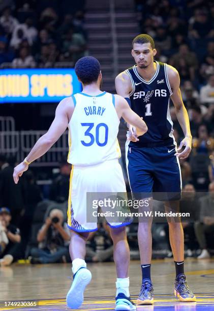 Victor Wembanyama of the San Antonio Spurs and Stephen Curry of the Golden State Warriors greet each other at center court right before they battle...