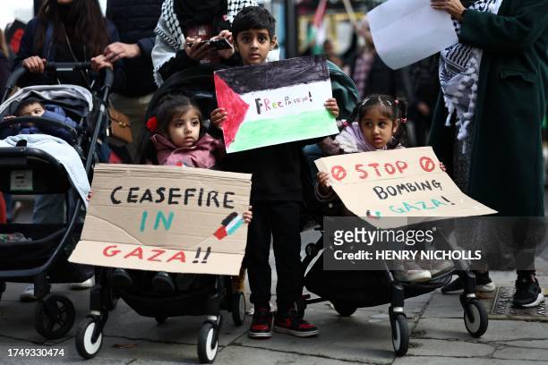 Young children pose with placards as they gather to take part in a 'March For Palestine' in London on October 28 to call for a ceasefire in the...
